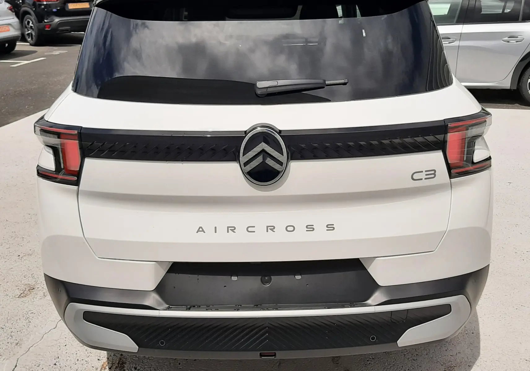 Vue arrière d'un Citroën C3 Aircross blanc banquise avec toit noir, feux arrière LED et logo central chromé.