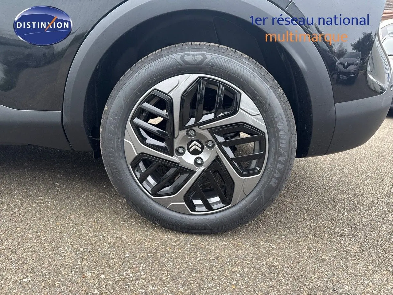 Gros plan sur la roue avant gauche noire métal d'une Citroën C4 2024 avec jante biton stylisée et logo Citroën central.