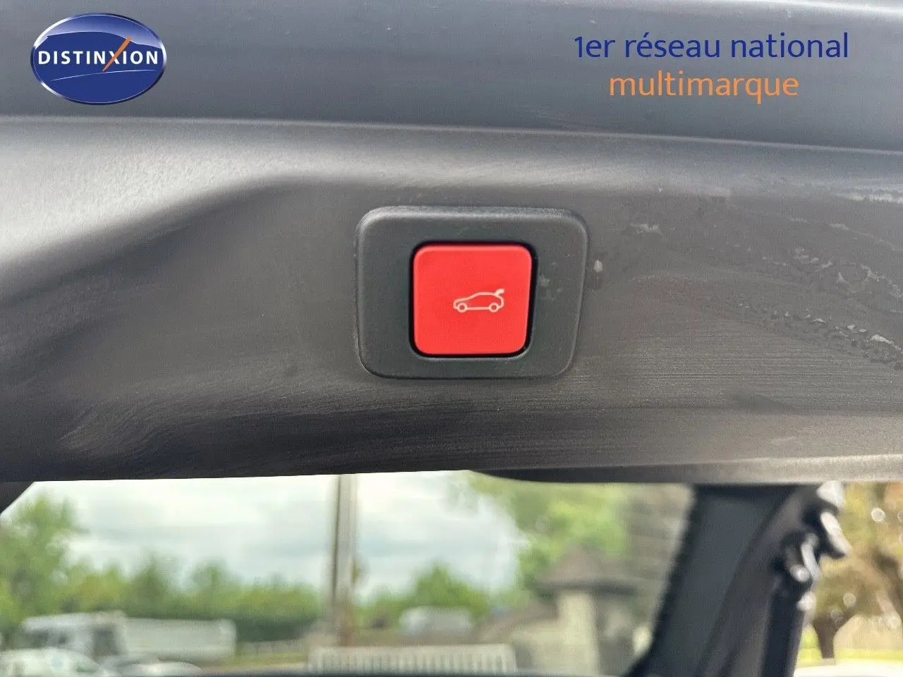 Bouton rouge d'ouverture électrique du hayon sur le bord intérieur d'un Peugeot 3008 Hybrid bleu Ingaro métal avec toit noir.