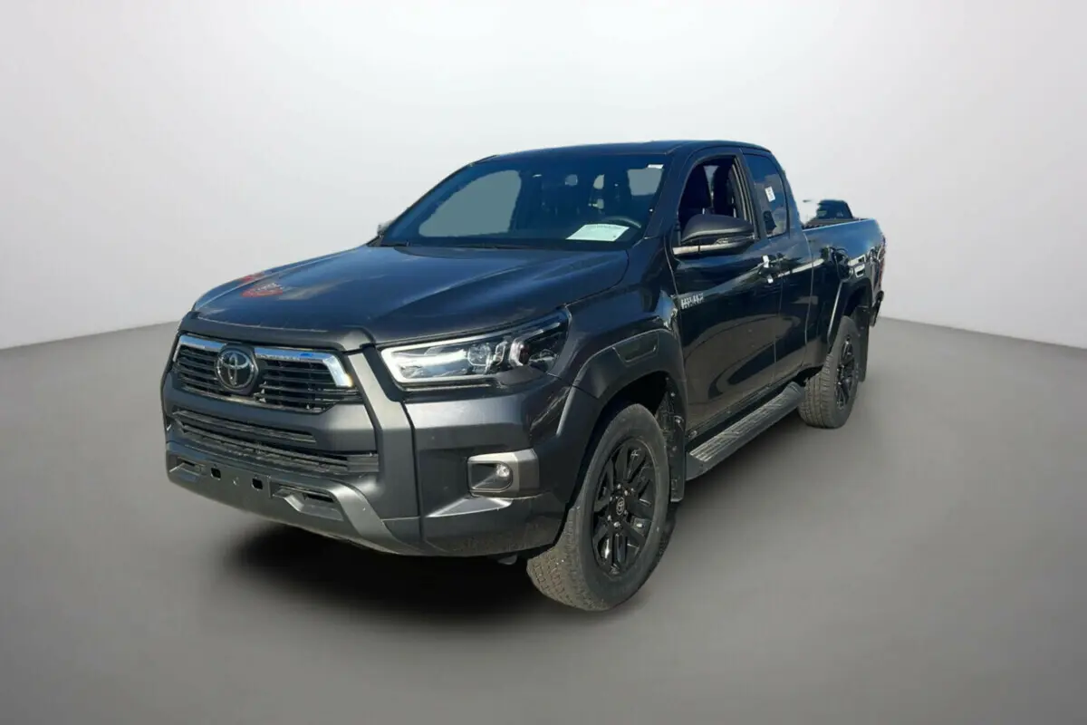 Toyota Hilux 4x4 Invincible gris atlas en 3/4 avant droit, avec jantes noires et calandre imposante.