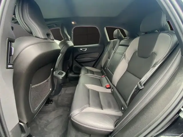Vue intérieure arrière du Volvo XC60 noir 2021, sièges en cuir noir et toit panoramique visible au-dessus.