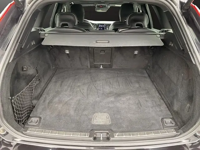 Coffre ouvert vu de l'arrière d'un Volvo XC60 noir, montrant l'espace de chargement et la plage arrière rétractable.