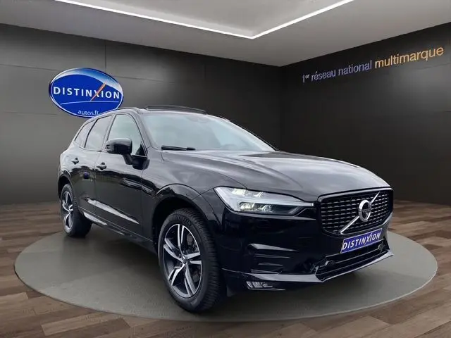 Vue 3/4 avant d'un Volvo XC60 noir 2021 R-Design avec toit panoramique, sur plateau en showroom Distinxion.