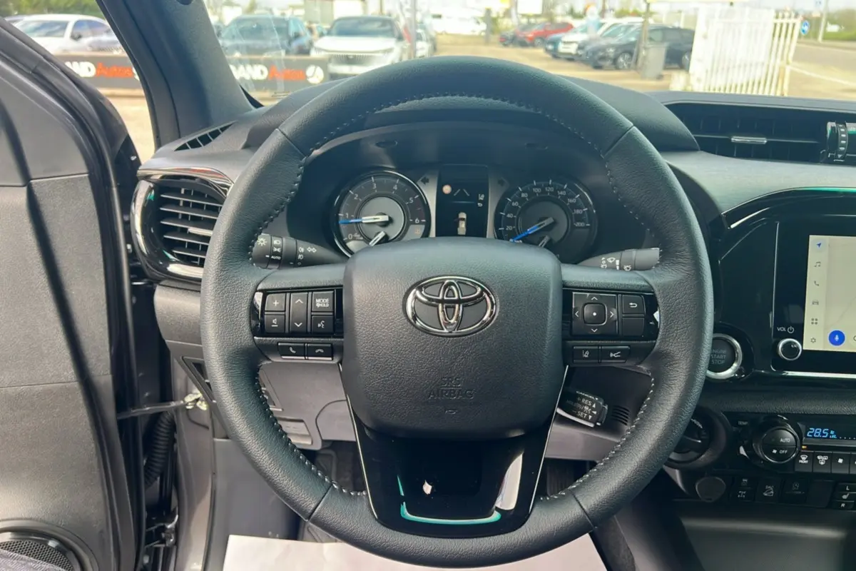 Vue rapprochée du volant et du tableau de bord du Toyota Hilux 2025 gris atlas, avec commandes intégrées et écran tactile.