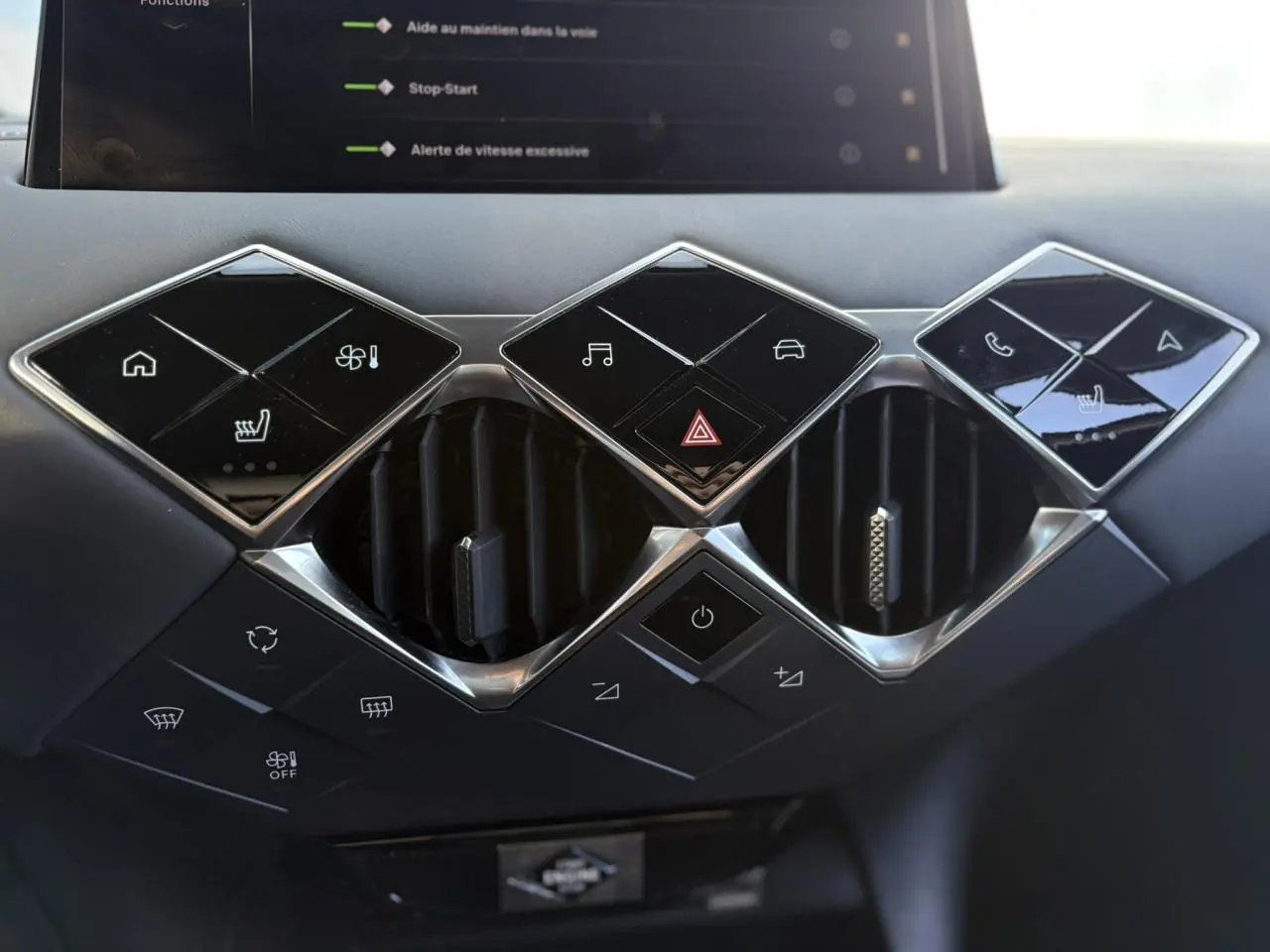 Vue rapprochée du tableau de bord noir du DS3 2024, montrant les commandes tactiles et les aérateurs en losange chromé.
