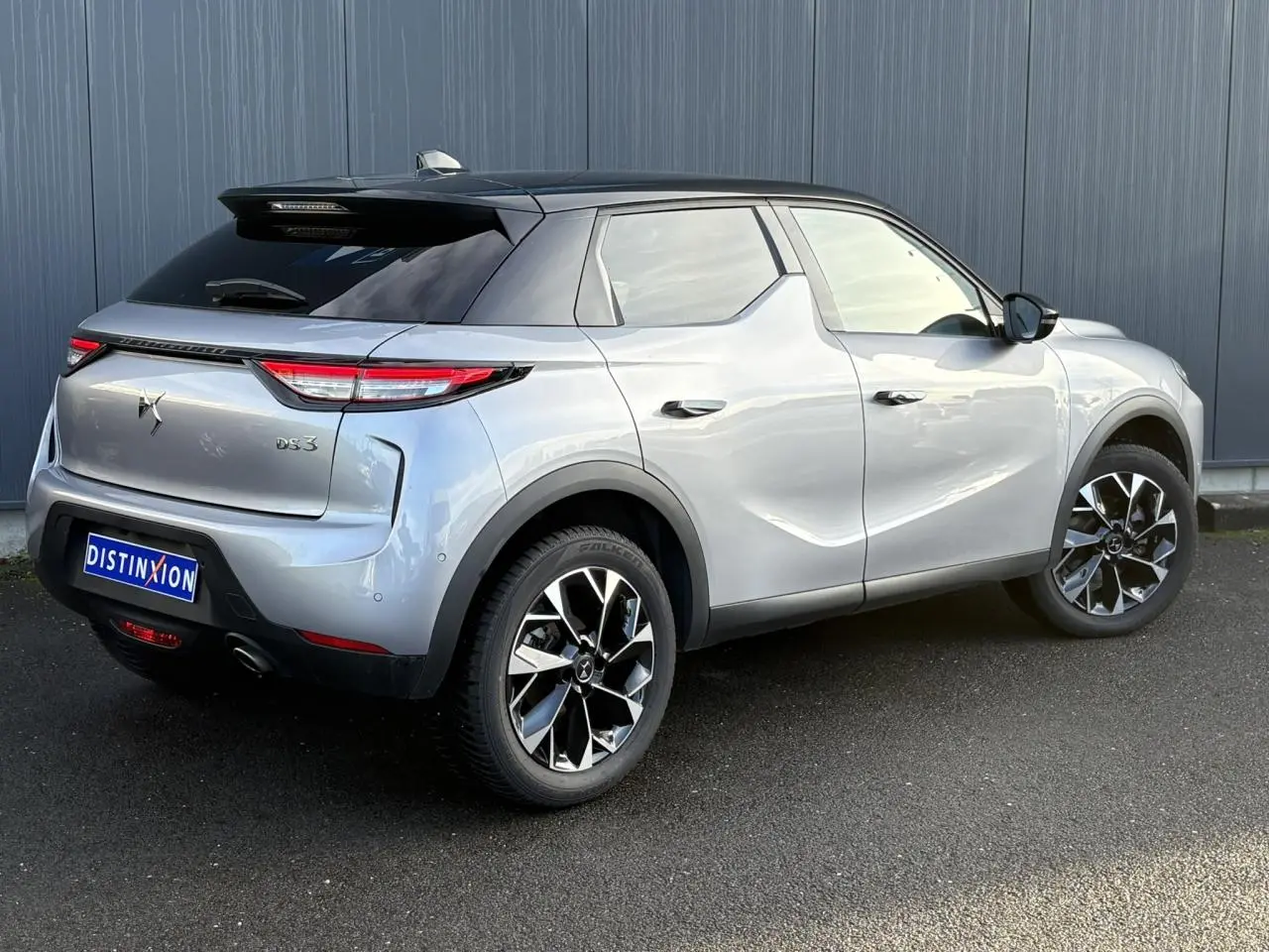 Vue 3/4 arrière droite du DS3 2024 gris Artense avec toit noir et jantes alliage 18 pouces distinctives.