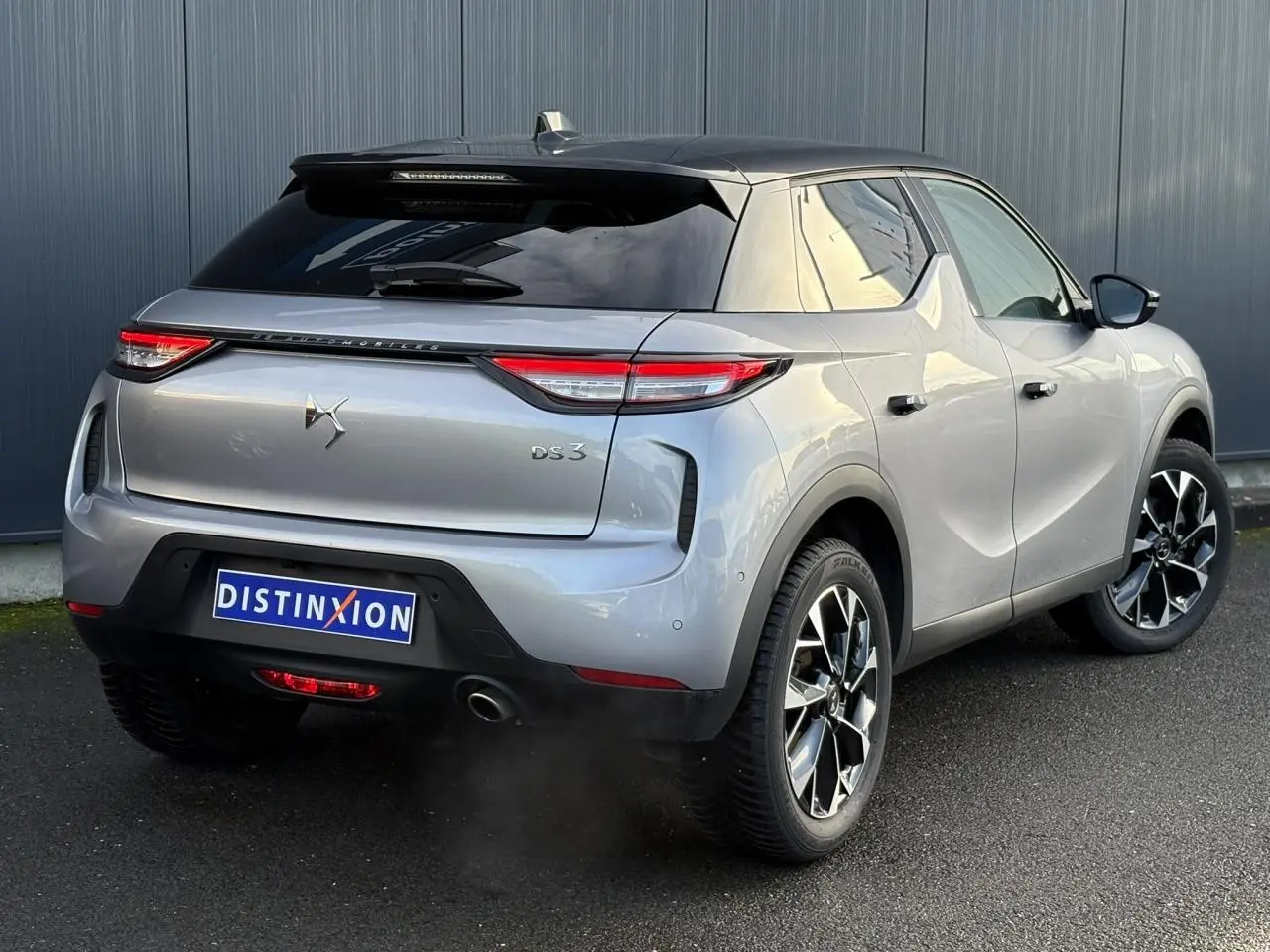 Vue 3/4 arrière droite d'un DS3 2024 gris Artense avec toit noir et jantes alliage noires et argentées.