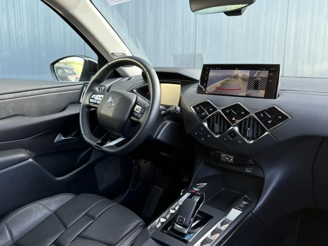 Vue 3/4 arrière droite d'une DS3 2024 gris Artense avec toit noir et jantes alliage noires.