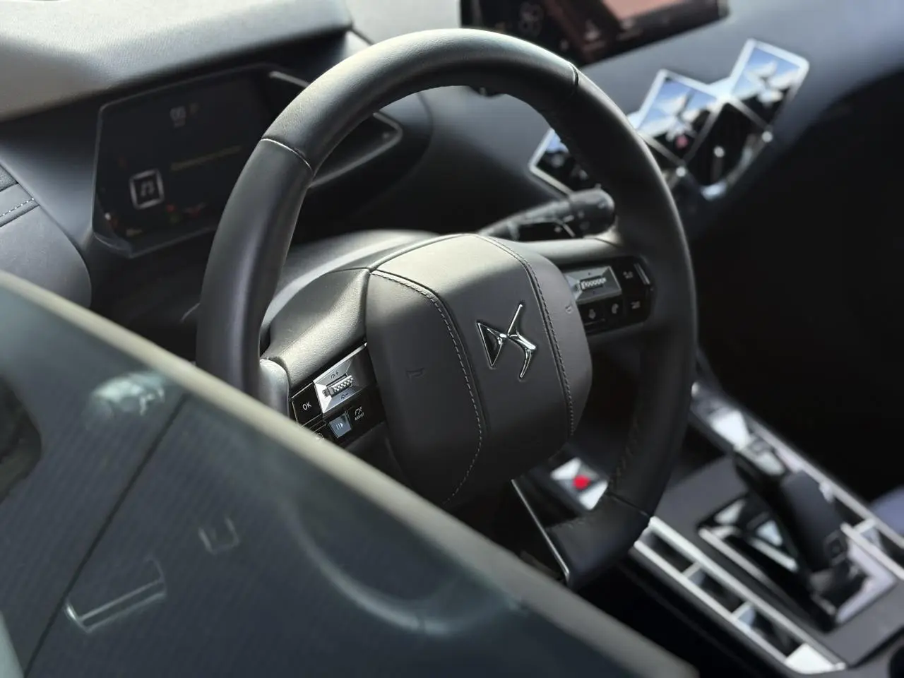 Vue rapprochée du volant cuir noir et du tableau de bord numérique intérieur du DS3 2024.