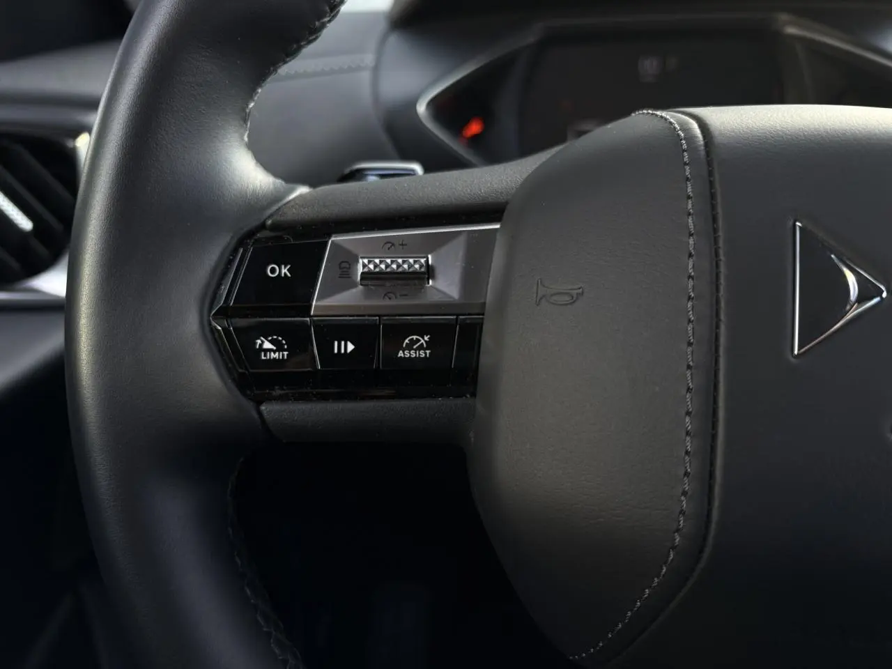 Gros plan sur le volant cuir noir du DS3 2024 avec commandes intégrées pour régulateur adaptatif et assistance.