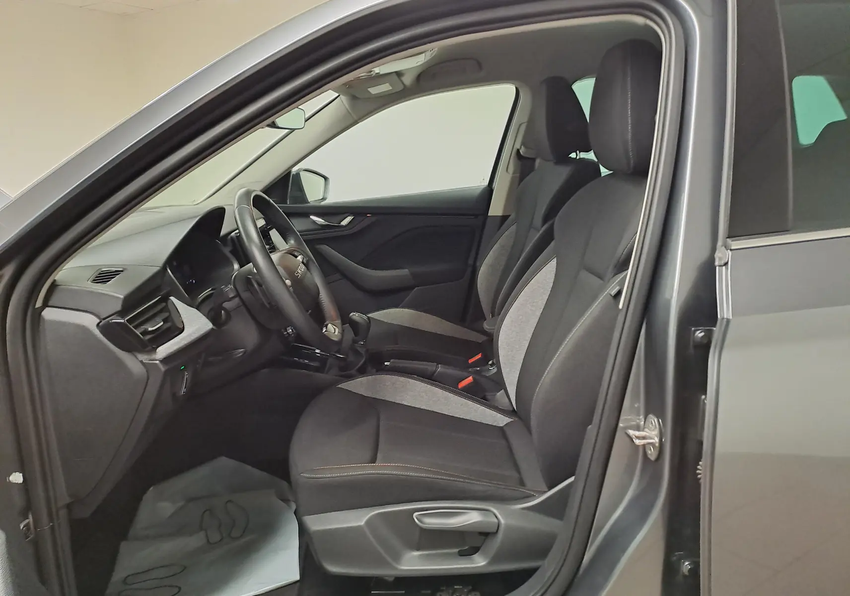 Vue intérieure côté conducteur du Skoda Kamiq gris graphite 2025, sièges tissu bicolore et tableau de bord moderne.