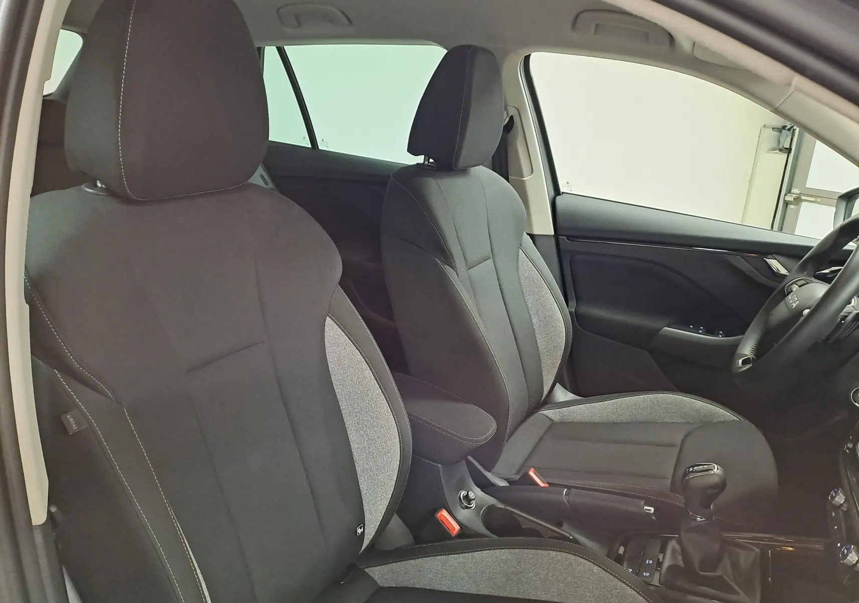 Vue intérieure côté conducteur du Skoda Kamiq 2025, sièges tissu noir et gris avec surpiqûres contrastées.