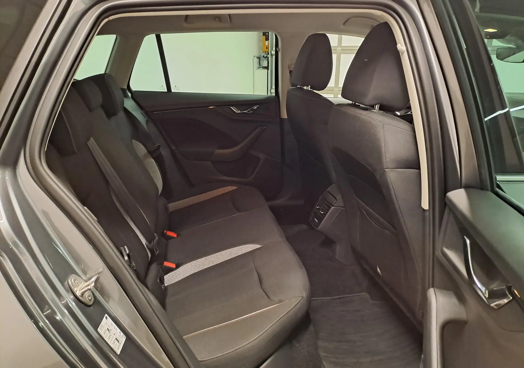 Vue intérieure côté gauche sur les sièges arrière noirs du Skoda Kamiq gris graphite avec porte ouverte.