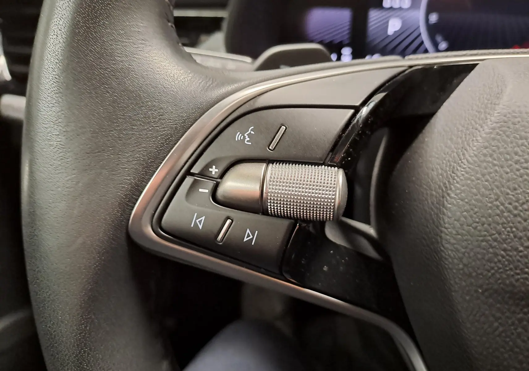 Gros plan sur les commandes audio au volant du Skoda Kamiq 2025, finition gris graphite avec molette métallique.