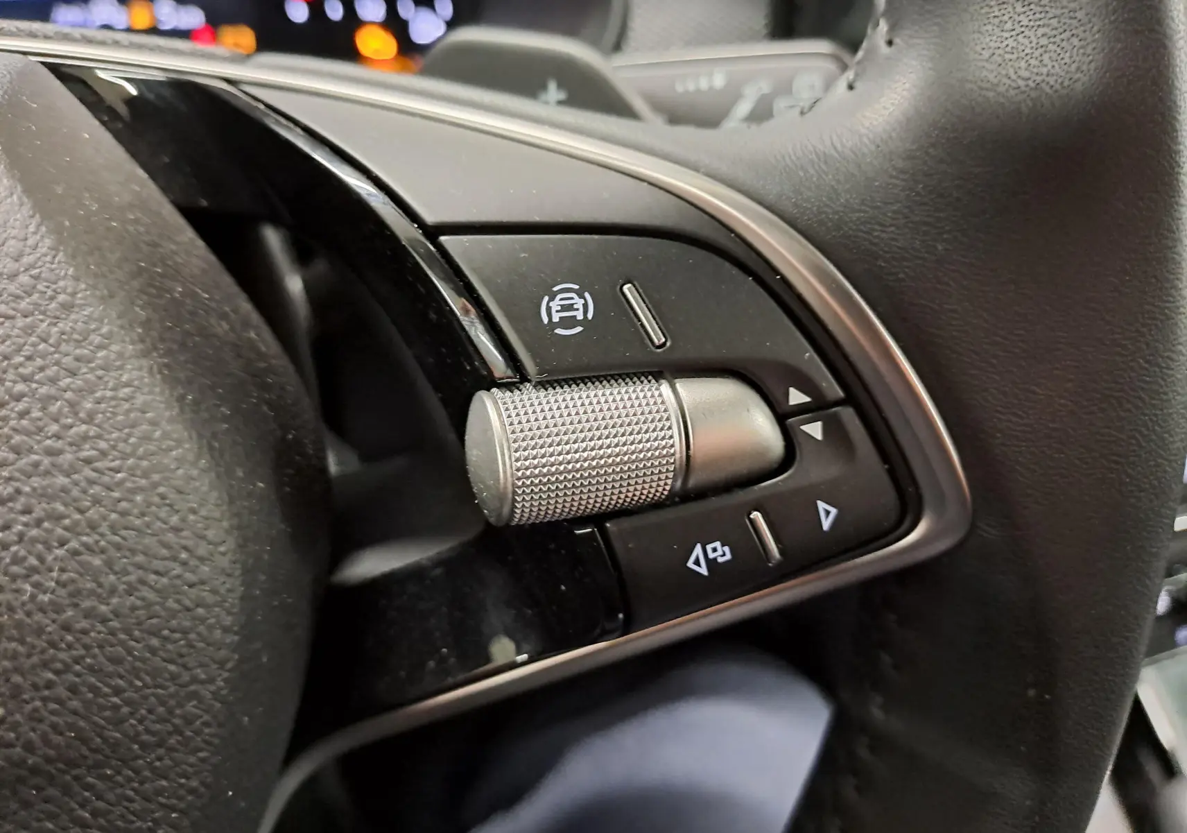 Gros plan sur les commandes au volant du Skoda Kamiq 2025, avec molette métallique et boutons noirs.