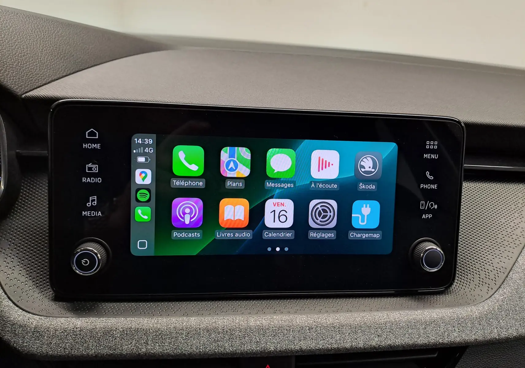 Écran tactile central du Skoda Kamiq 2025 affichant des applications connectées, entouré de commandes noires sur tableau de bord gris.