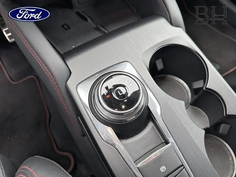Vue rapprochée de la molette de boîte automatique et porte-gobelets sur la console centrale grise du Ford Kuga 2024.