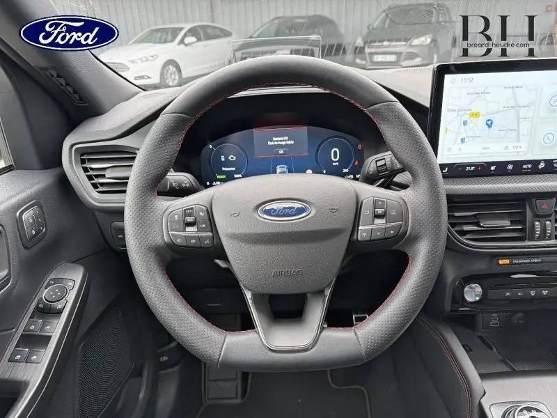Vue intérieure centrée sur le volant sport du Ford Kuga 2024 avec tableau de bord numérique et écran tactile GPS.