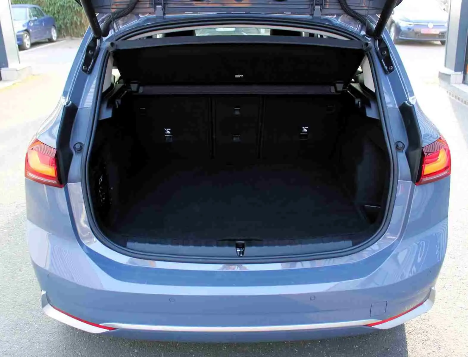 Vue arrière ouverte sur le coffre spacieux d'une BMW Série 2 Active Tourer gris Nardo métal avec feux arrière allumés.