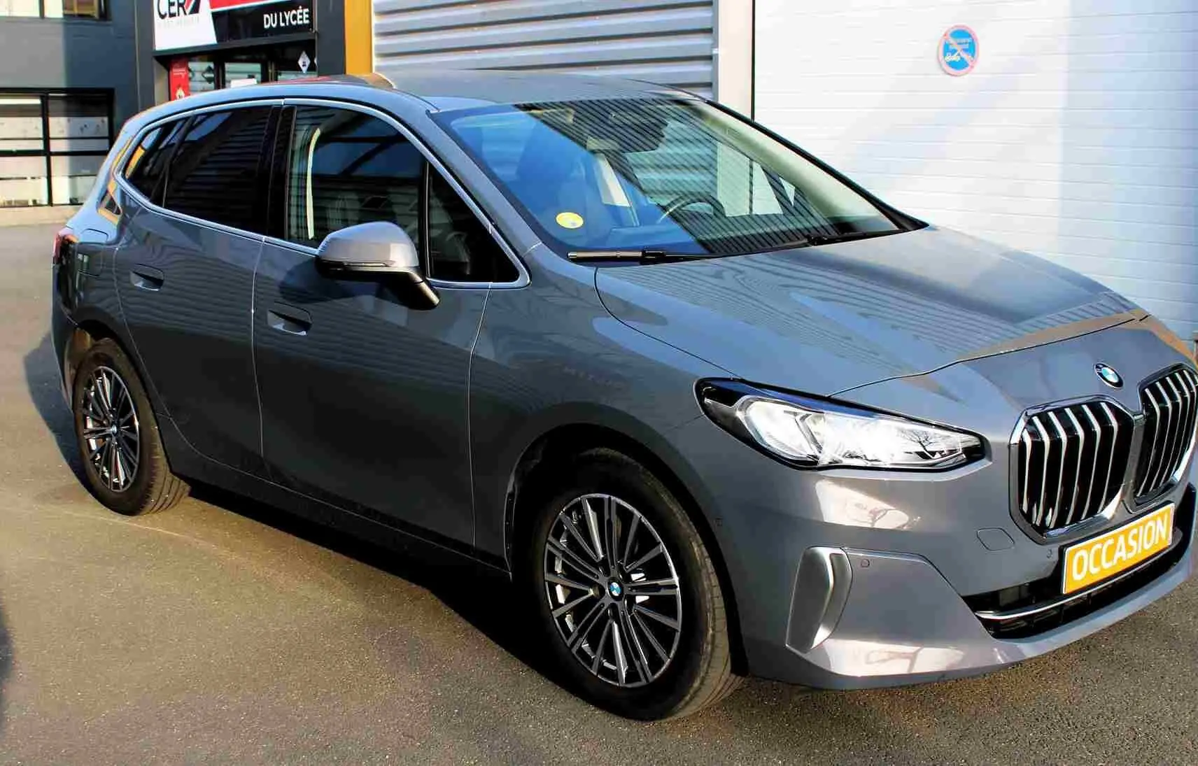 BMW Série 2 Active Tourer gris Nardo métal vue 3/4 avant droit avec calandre imposante et jantes alliage.