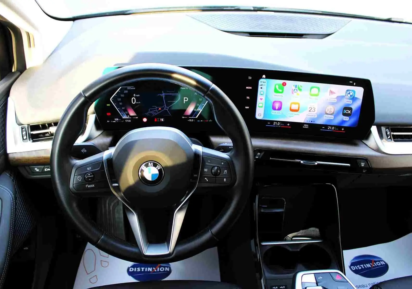 Vue intérieure centrée sur le volant cuir noir et l'écran tactile large du tableau de bord du BMW Série 2 Active Tourer gris Nardo.