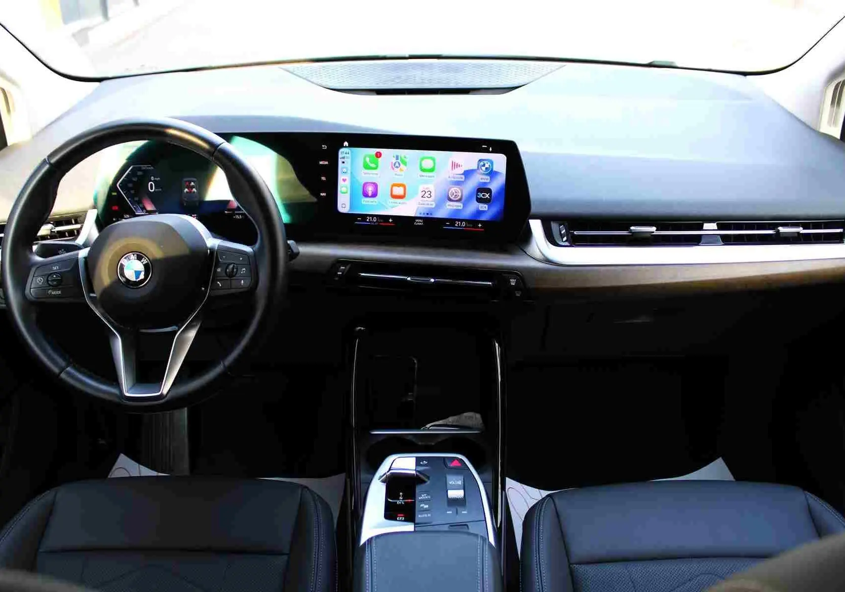 Vue intérieure frontale du tableau de bord de la BMW Série 2 Active Tourer 218d 2023 avec écran tactile et volant cuir noir.