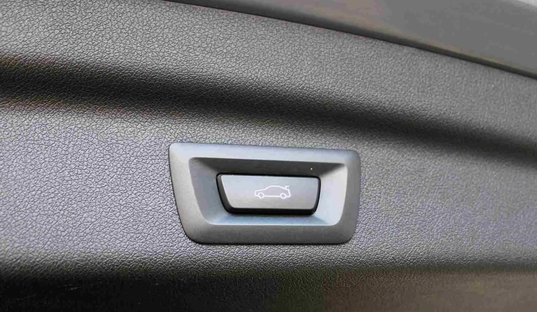Bouton d'ouverture électrique du hayon sur panneau intérieur noir d'une BMW Série 2 Active Tourer gris Nardo.