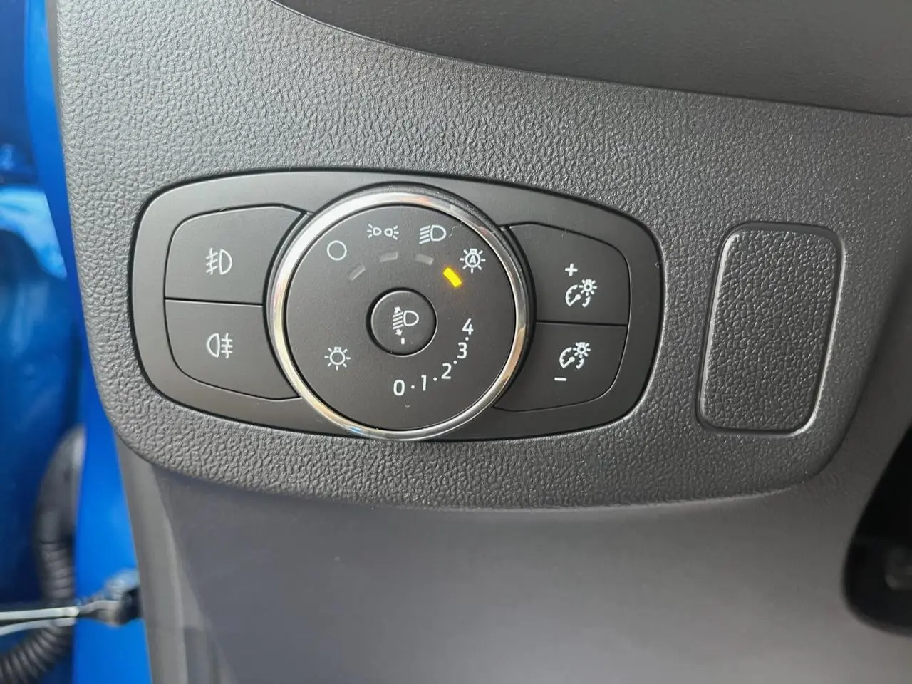 Gros plan sur la molette de réglage des phares du Ford Puma bleu 2022, avec commandes d'éclairage et antibrouillard.