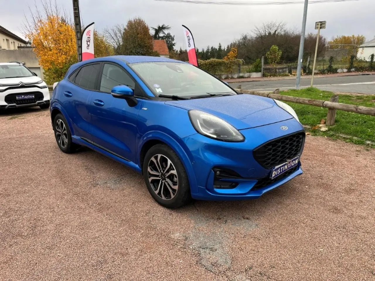 Ford Puma bleu métallisé en vue 3/4 avant droit, avec jantes alliage noires et vitres arrière surteintées.