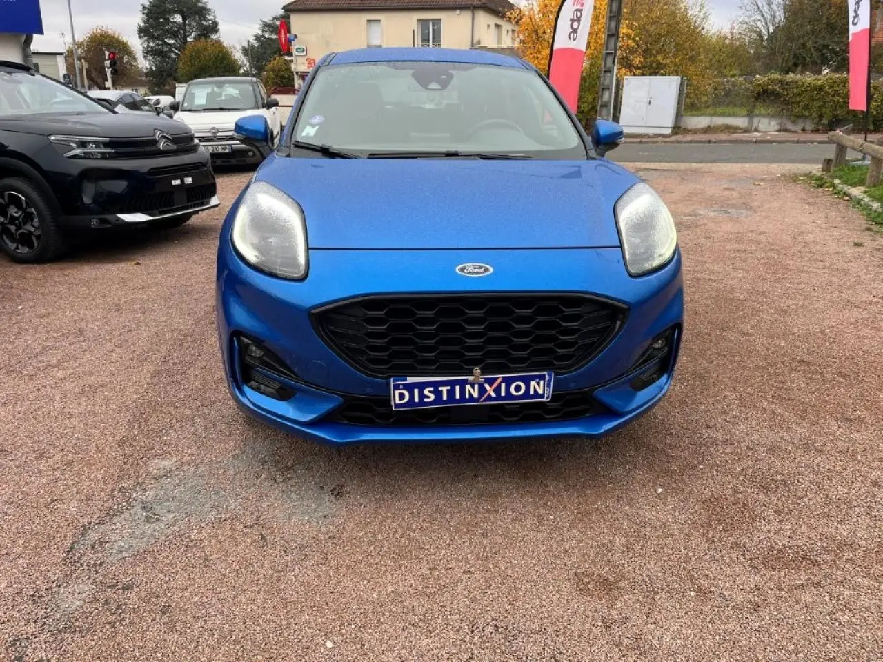 Vue frontale d'une Ford Puma bleu métallisé avec calandre noire et phares LED, sur un parking extérieur.