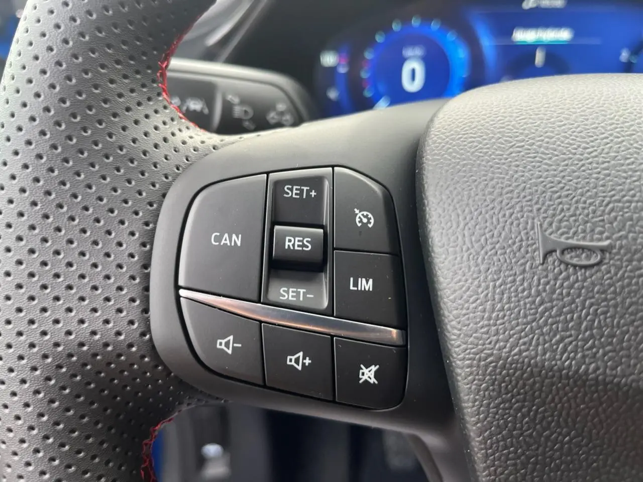Gros plan sur les commandes de régulateur de vitesse et volume au volant perforé du Ford Puma 2022.