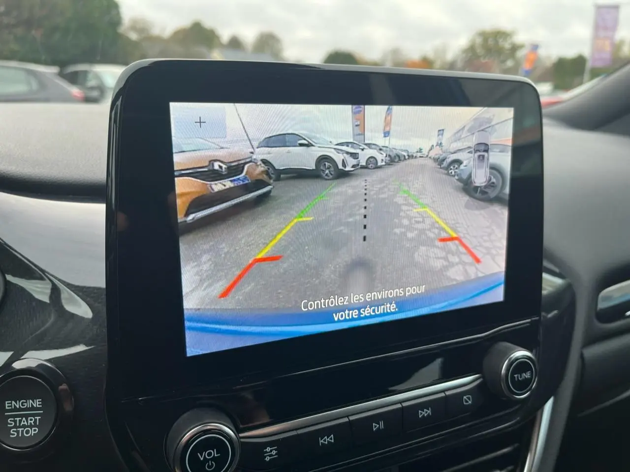 Écran tactile intérieur montrant la caméra de recul du Ford Puma bleu avec lignes d’aide au stationnement colorées.