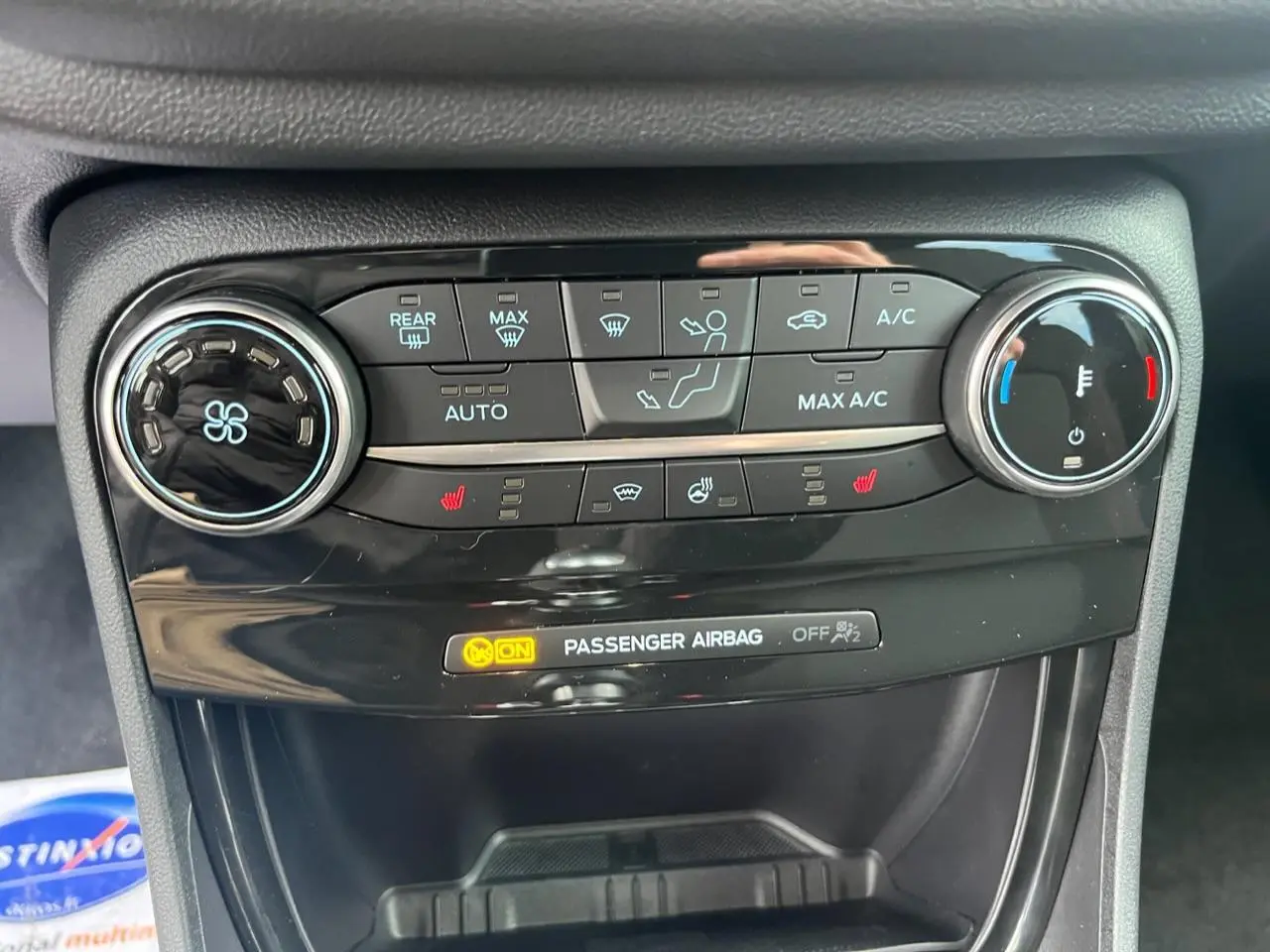 Vue rapprochée de la console de climatisation du Ford Puma bleu, avec commandes digitales et réglages chauffants visibles.