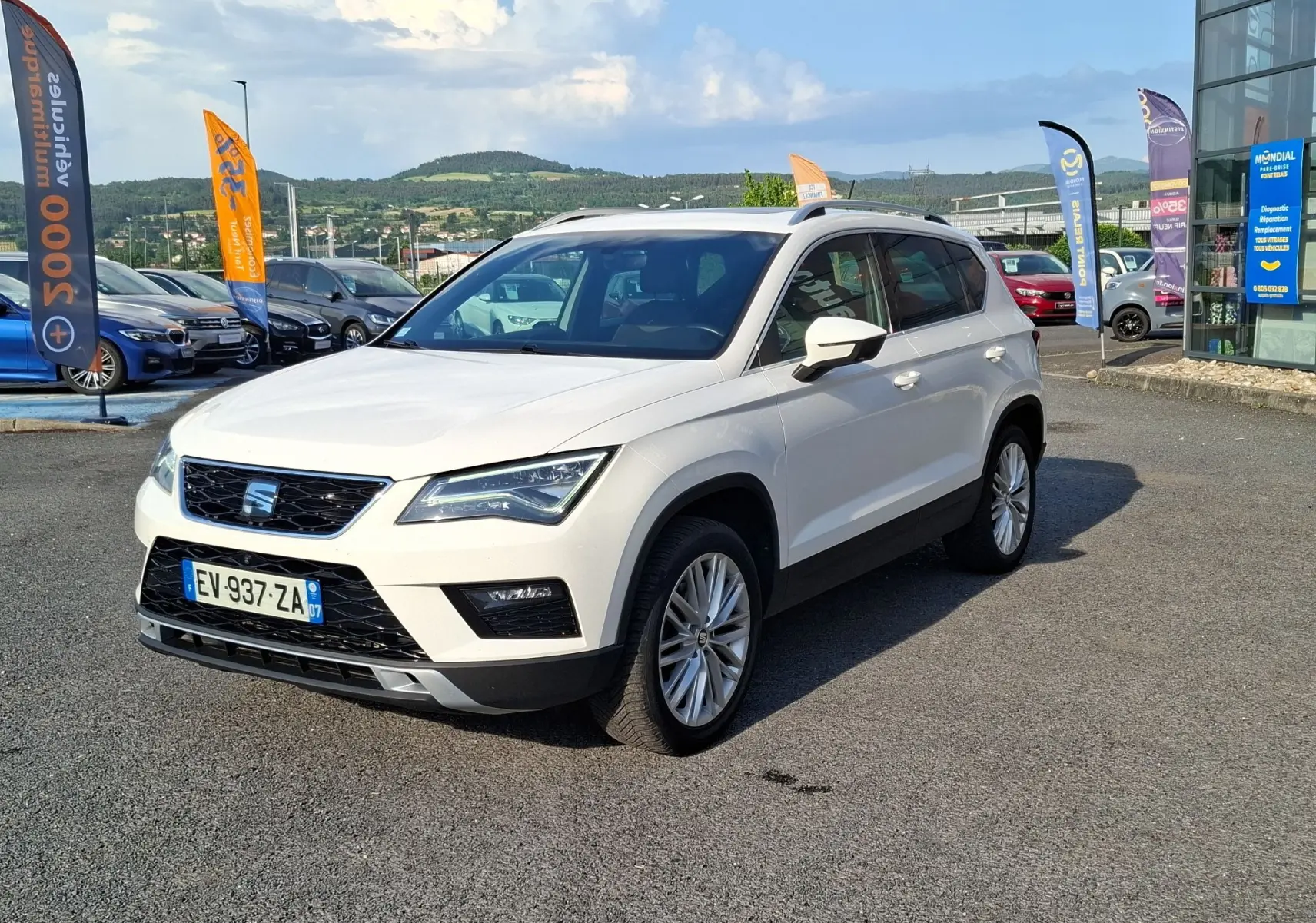 SEAT Ateca blanc 2018 en 3/4 avant droit, avec jantes alliage et barres de toit visibles.