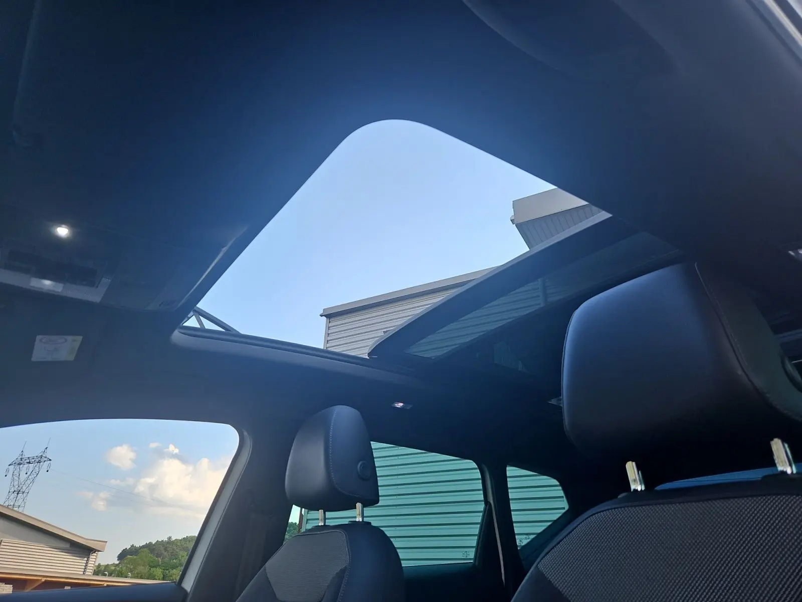 Vue intérieure du toit panoramique ouvert et des sièges avant en cuir noir du SEAT Ateca blanc 2018.