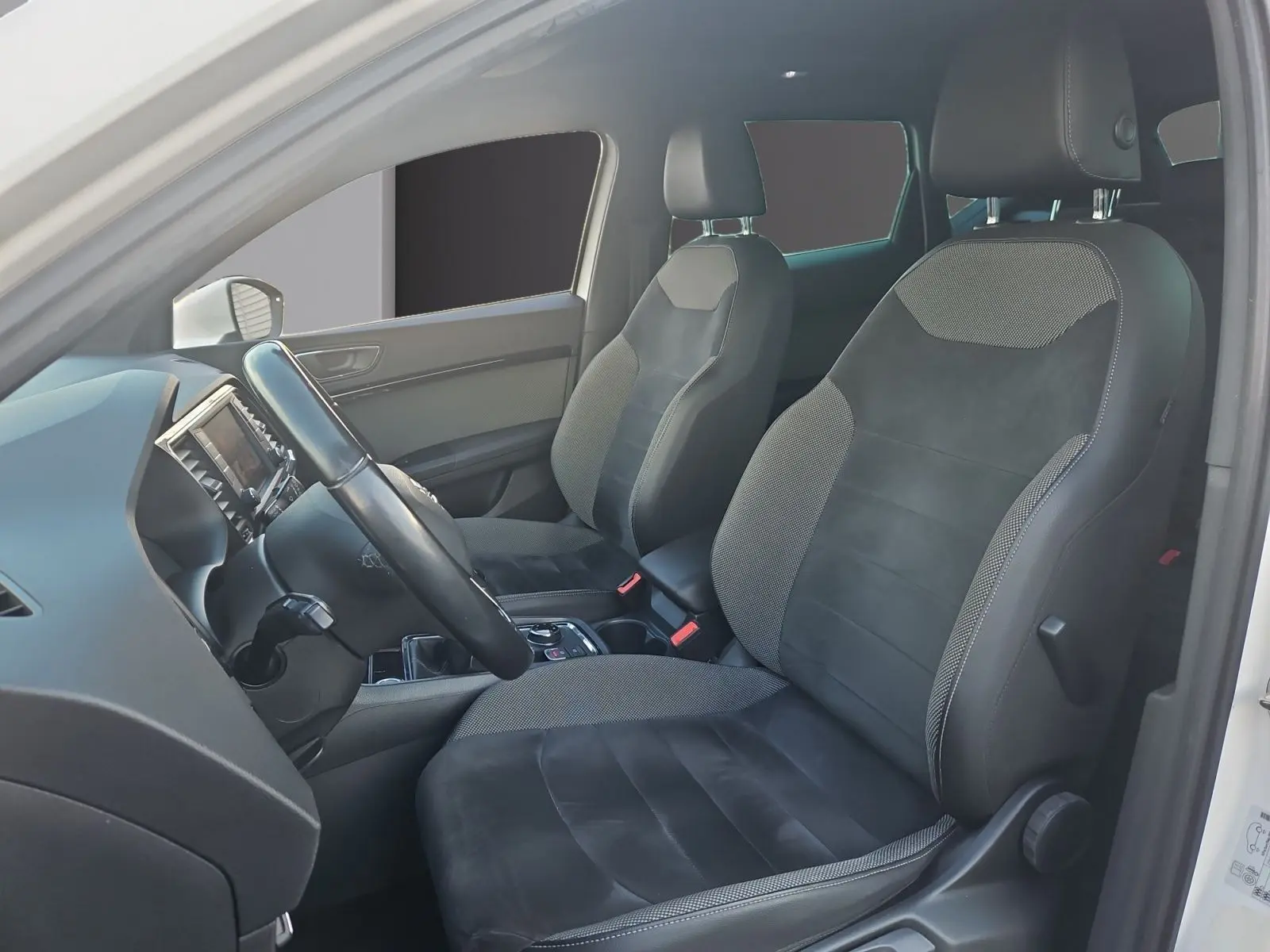 Vue intérieure côté conducteur du SEAT Ateca blanc, mettant en valeur les sièges en cuir et alcantara noirs.