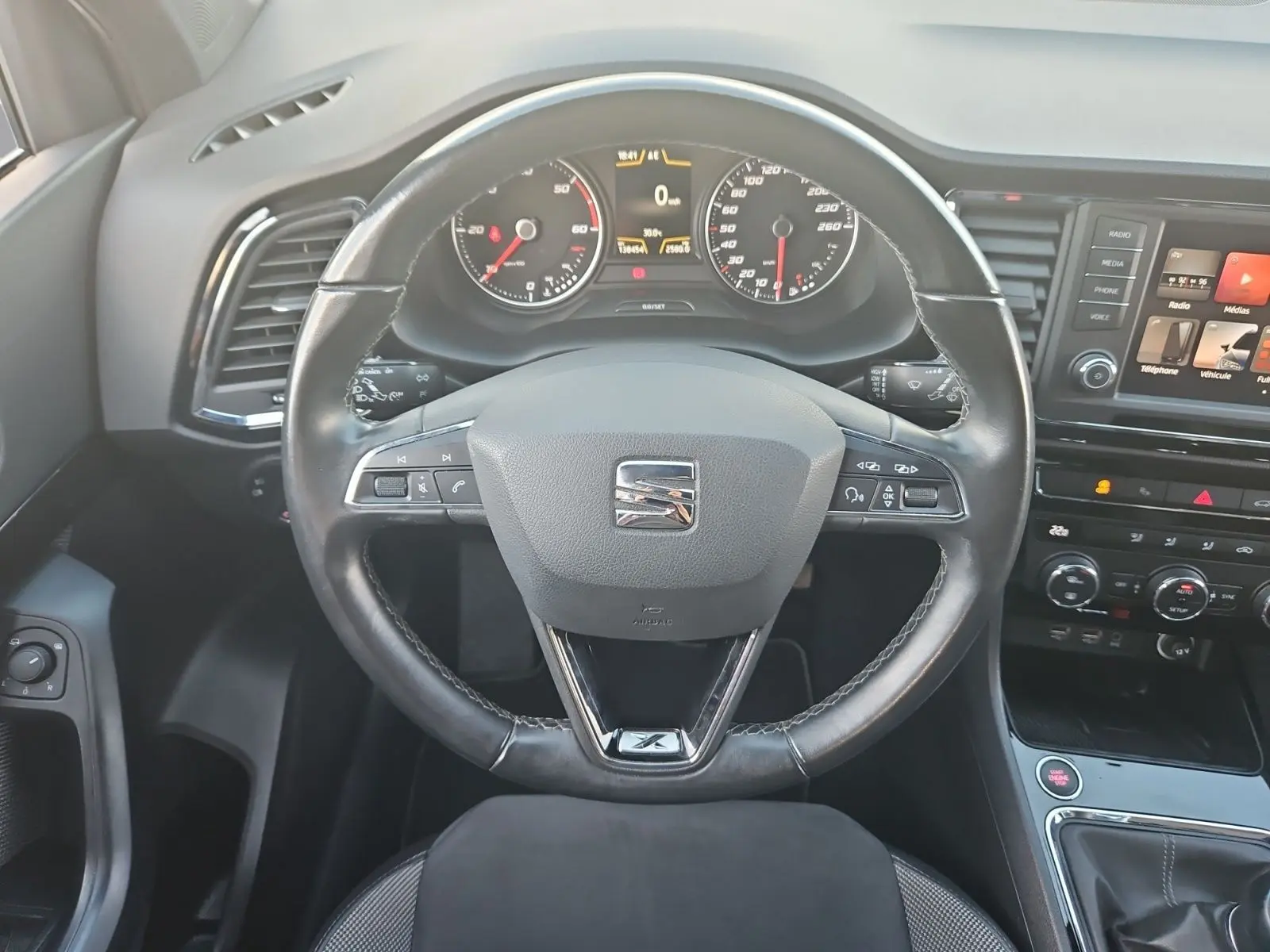 Vue intérieure centrée sur le volant cuir noir et le tableau de bord du SEAT Ateca blanc 2018.