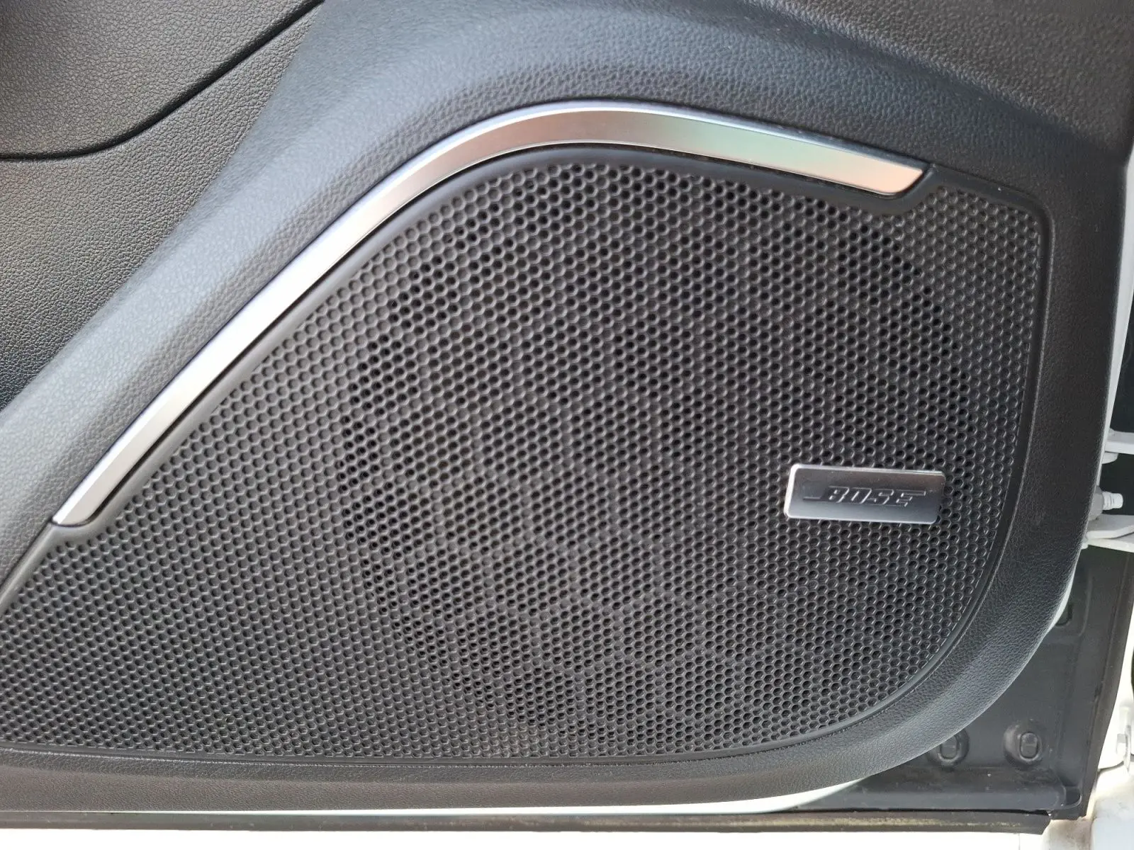 Gros plan sur l'enceinte Bose intégrée à la porte avant droite d'une Renault Mégane blanche.