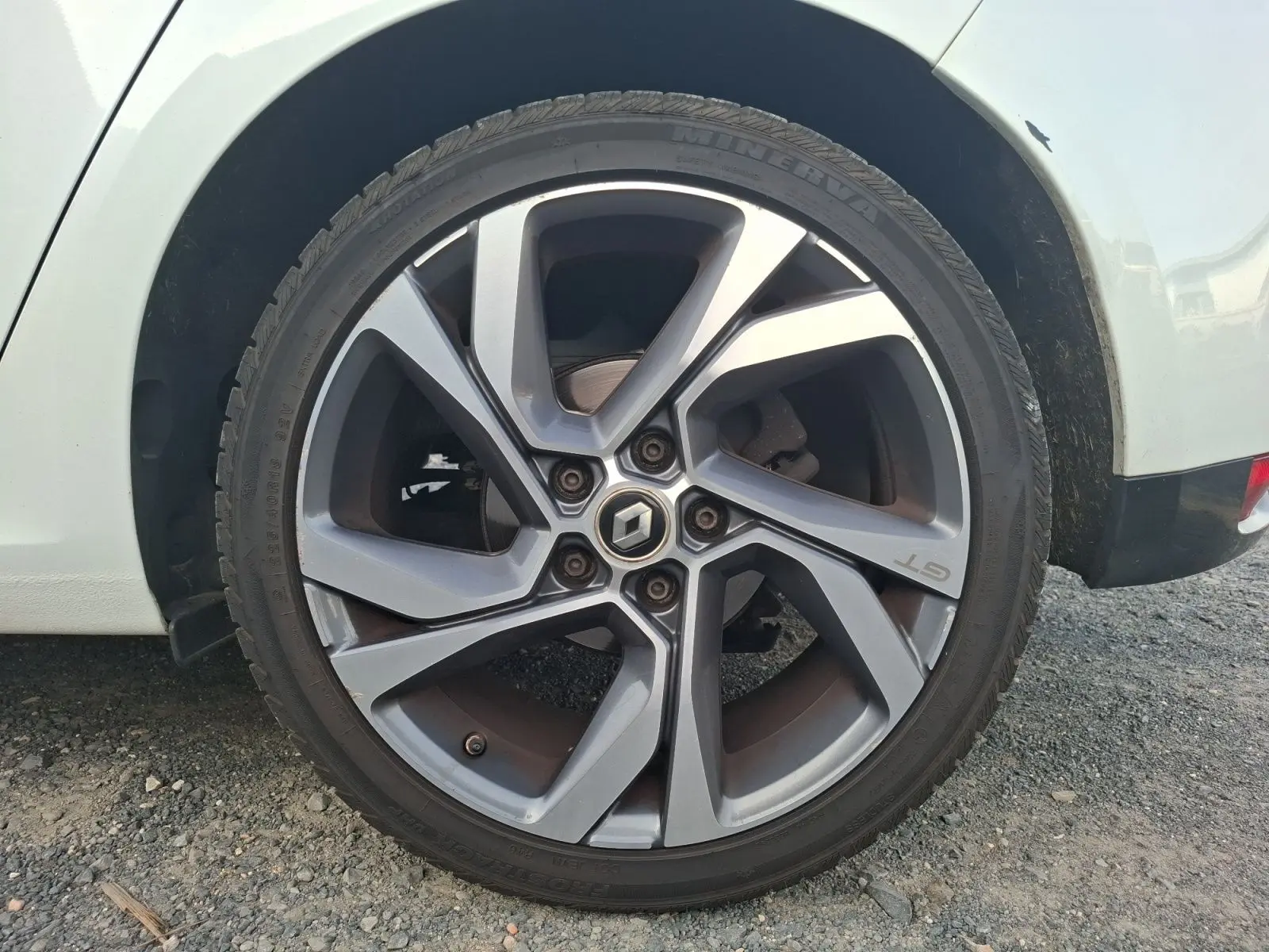 Gros plan sur la roue arrière droite d’une Renault Mégane blanche, jante alliage gris foncé GT 15 pouces.