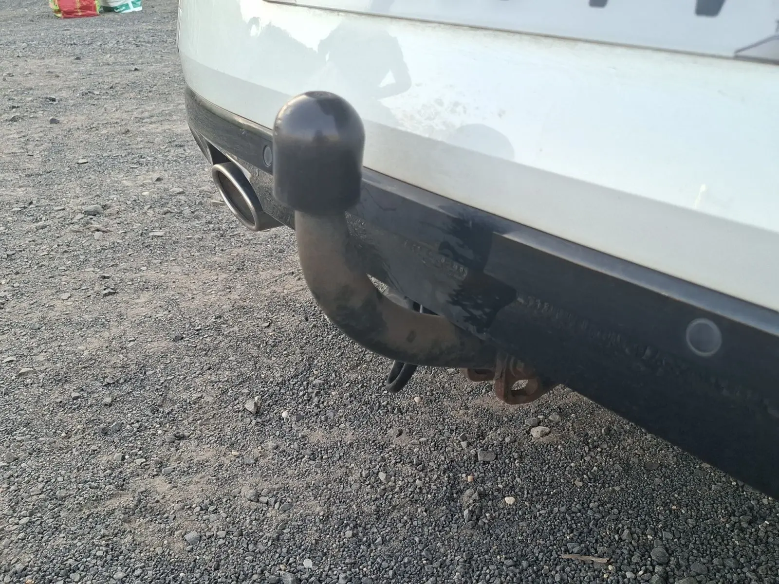 Gros plan sur l'attelage arrière noir d'une Renault Mégane blanche, avec sortie d'échappement visible à gauche.