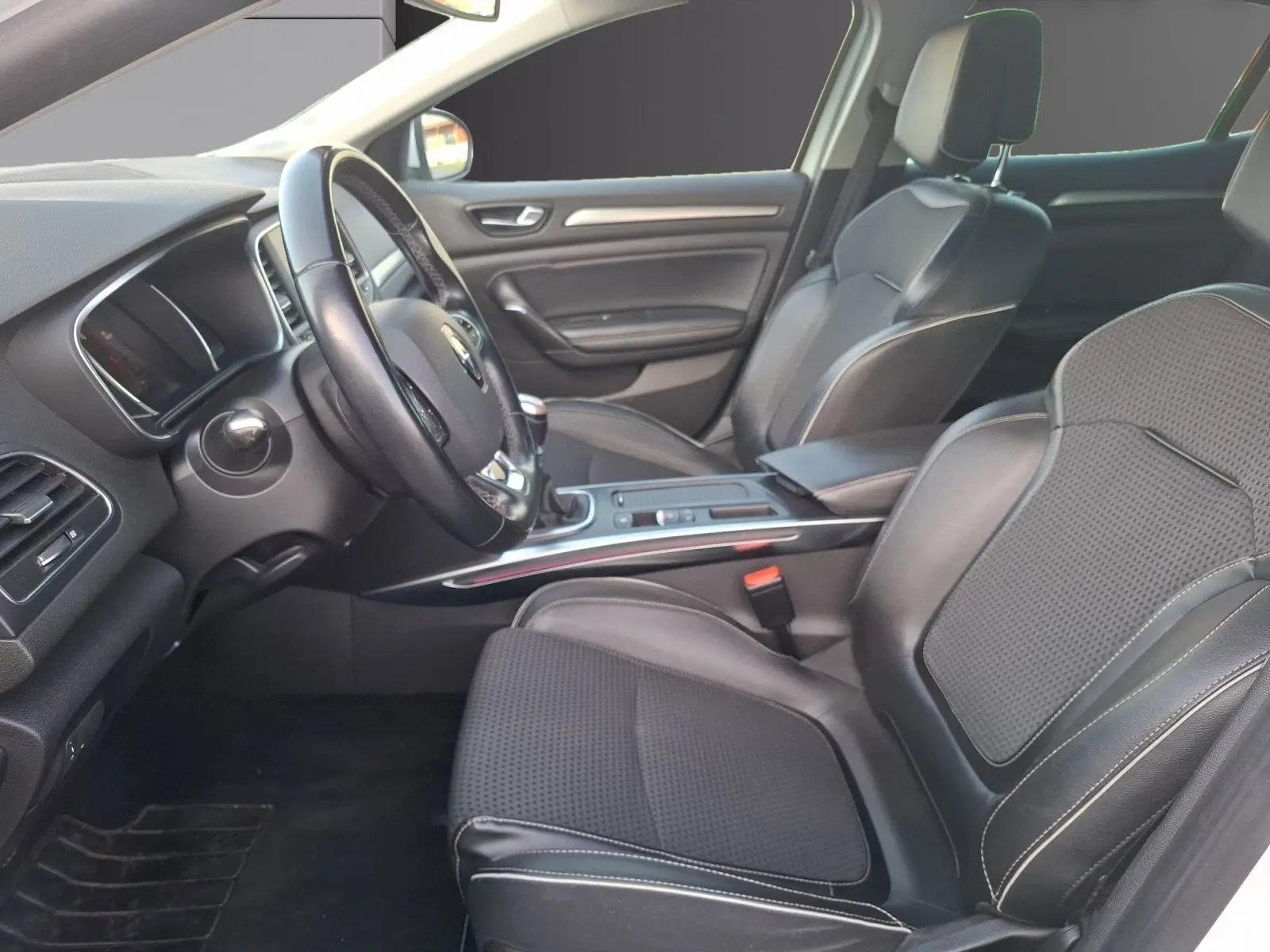Intérieur avant droit de la Renault Mégane blanc, sièges en cuir noir avec coutures blanches et tableau de bord moderne.