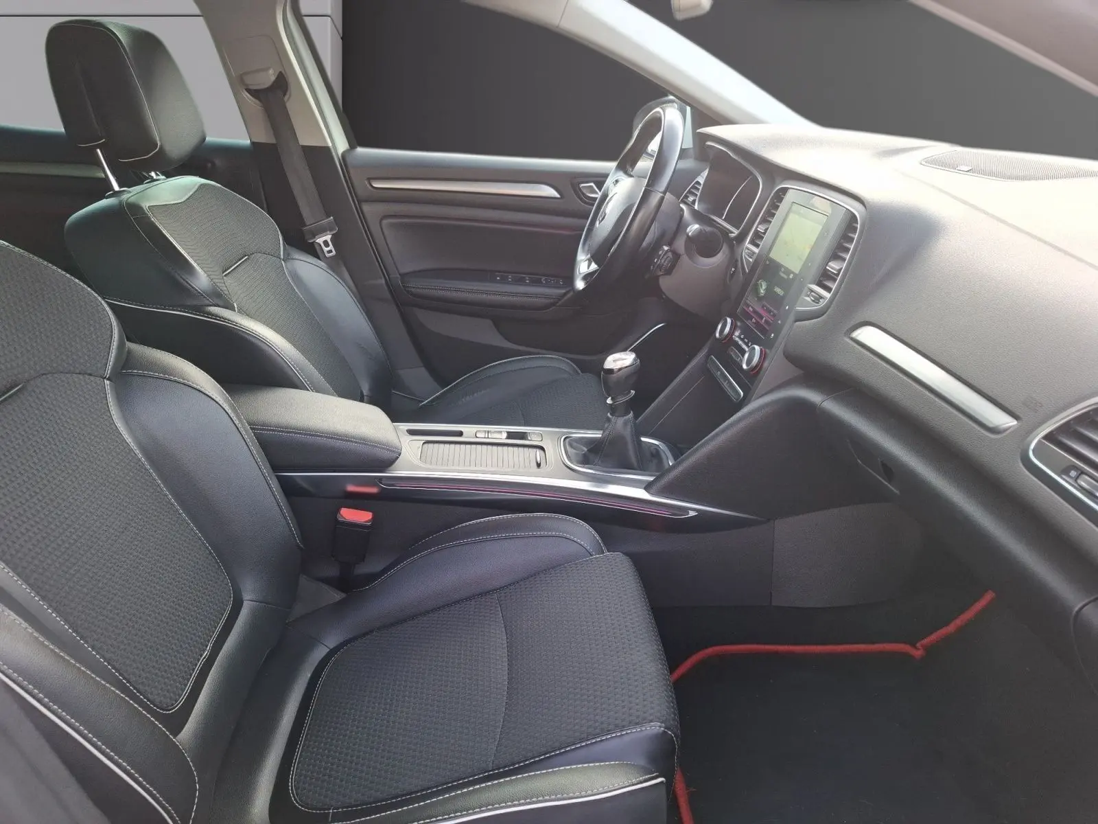 Vue intérieure côté conducteur de la Renault Mégane 1.6 DCI 130 Energy Intens 2016 avec sièges noirs et console centrale manuelle.