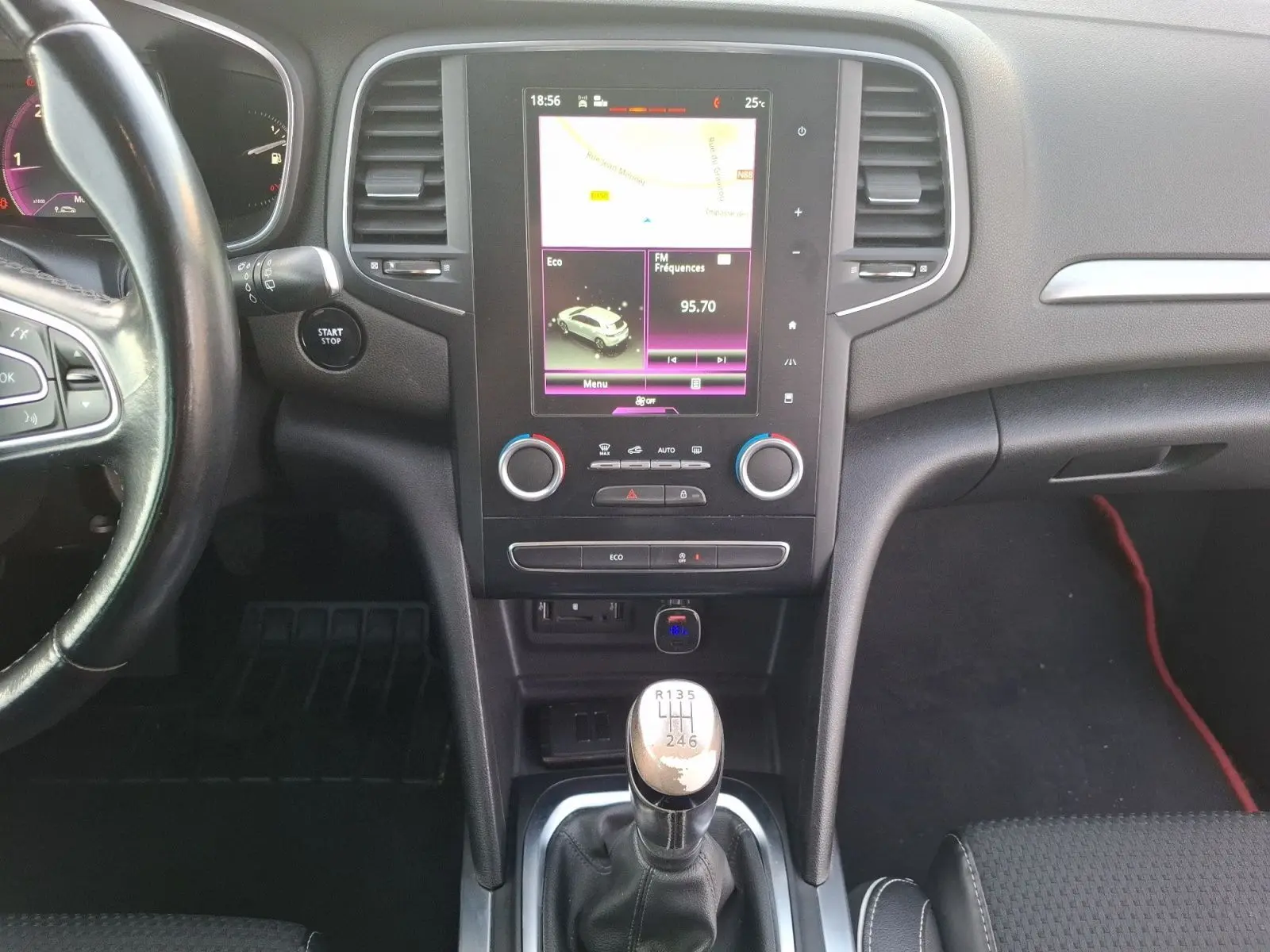 Vue intérieure centrée sur la console centrale et levier de vitesses manuelle d'une Renault Mégane blanche de 2016.