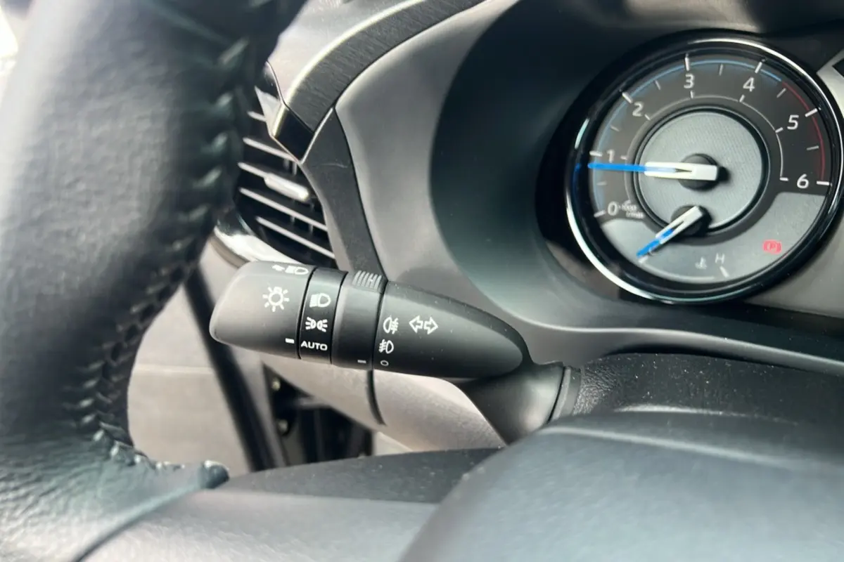 Gros plan sur le commodo des phares et compte-tours du tableau de bord du Toyota Hilux 2025, intérieur noir.