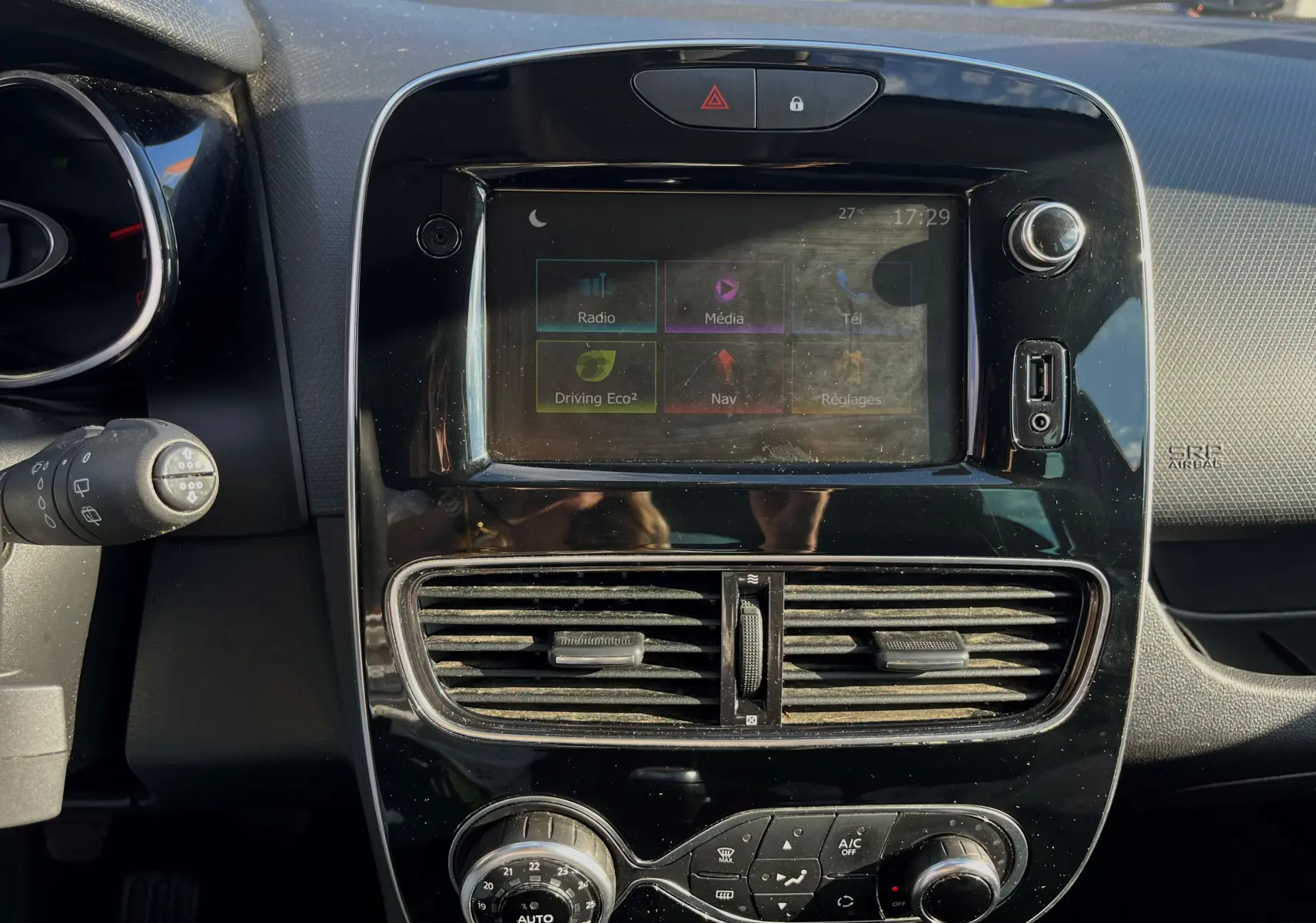 Le levier de vitesses manuel argenté de la Renault Clio IV 2019, entouré de sièges en tissu noir.