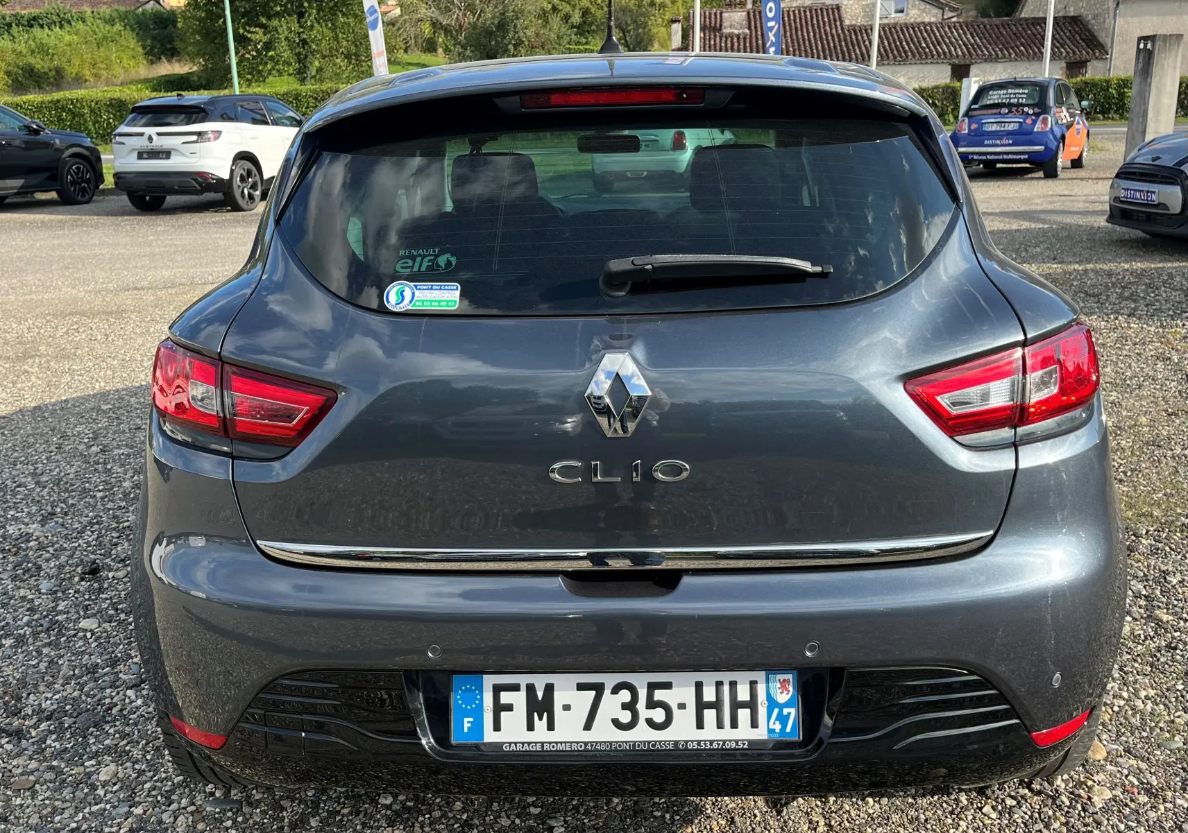 Vue arrière d'une Renault Clio IV grise foncée de 2019 avec plaques françaises et feux arrière allumés.