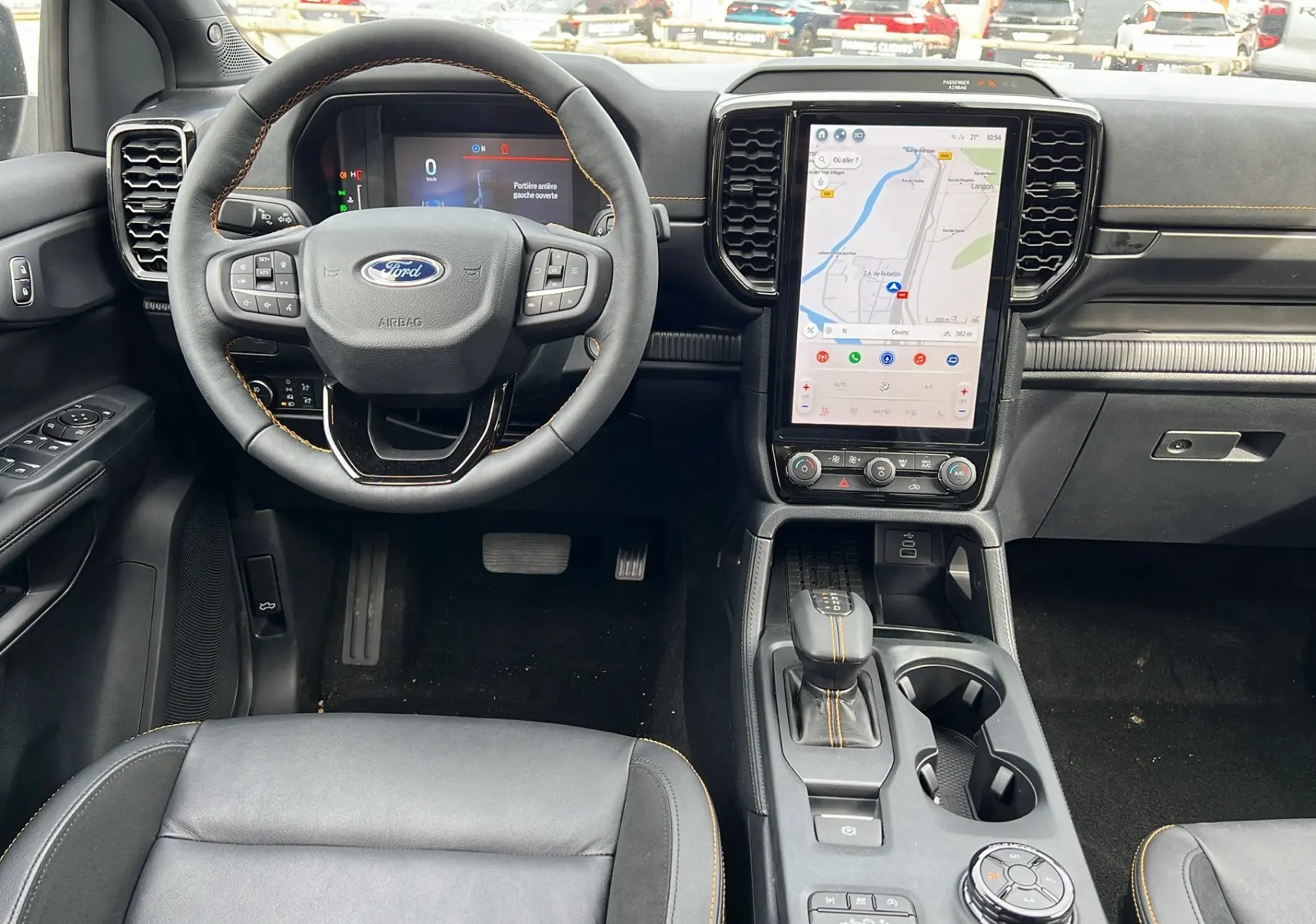Intérieur du Ford Ranger 2025 Wildtrak en vue frontale, tableau de bord noir avec écran tactile vertical et coutures orange.