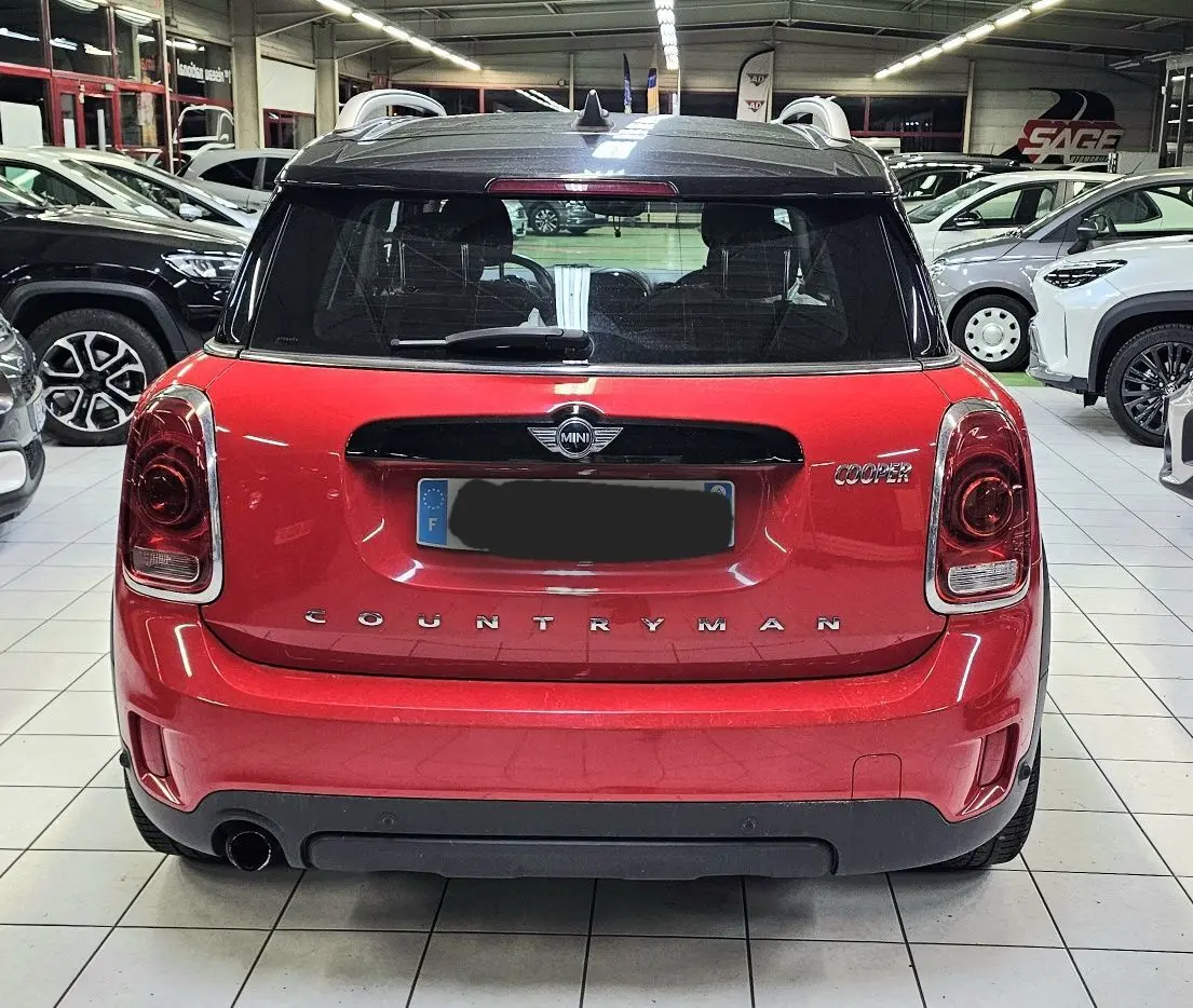 Vue arrière d'une MINI Cooper Countryman rouge avec toit noir, dans un showroom lumineux.