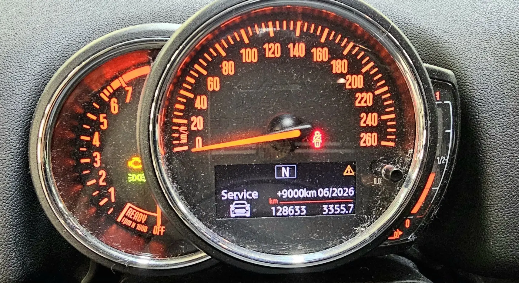 Gros plan sur le tableau de bord du MINI Cooper Countryman rouge, affichant le compteur de vitesse et le compte-tours éclairés en orange.