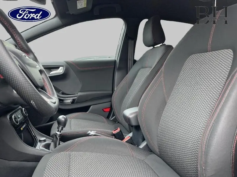 Vue intérieure côté conducteur du Ford Puma noir, mettant en valeur les sièges sport avec surpiqûres rouges et la boîte manuelle.
